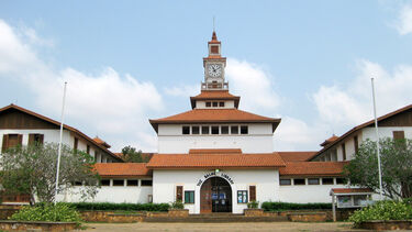 Image of a white building with red roofing and a clocktower.