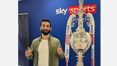 Ali working at Sky, stood next to a trophy at Sky sports
