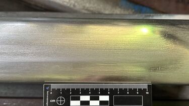 Plan view photo of laser clad railway rail with a scale marker next to it.