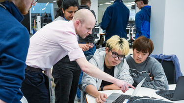 supervisor and computer science students looking at screen