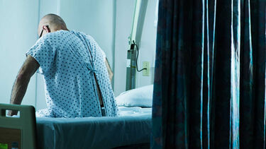 male patient sat on hospital bed looking worried