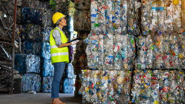 Female worker stood by plastic recycling piles