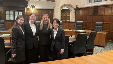4 students pose in a court room