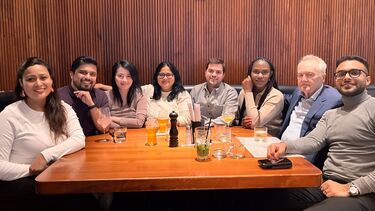 Sheffield alumni from all ages gathering around a table smiling at the camera.