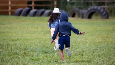 Two children running in a grassy play area