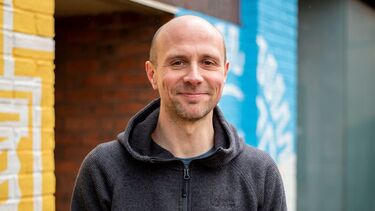 Dan Olner stood outside a yellow and blue wall 