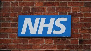 The NHS logo on a brick wall.