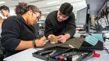 Two students are working together to fix a circuit in the E&C lab