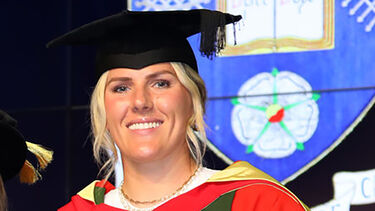 Millie Bright smiling in her honorary graduation robes