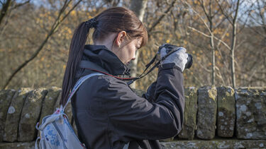 Student in nature taking photograph