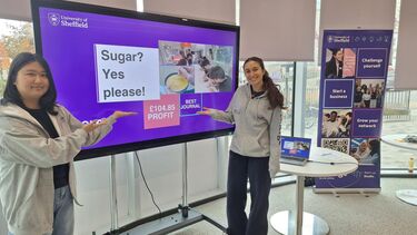 Two team members standing and pointing at screen with profit margin of £104.85