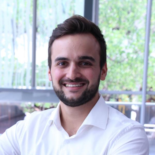 Profile picture of A photo of a man smiling at the camera. He has dark hair and a beard, and is wearing a white collared shirt.