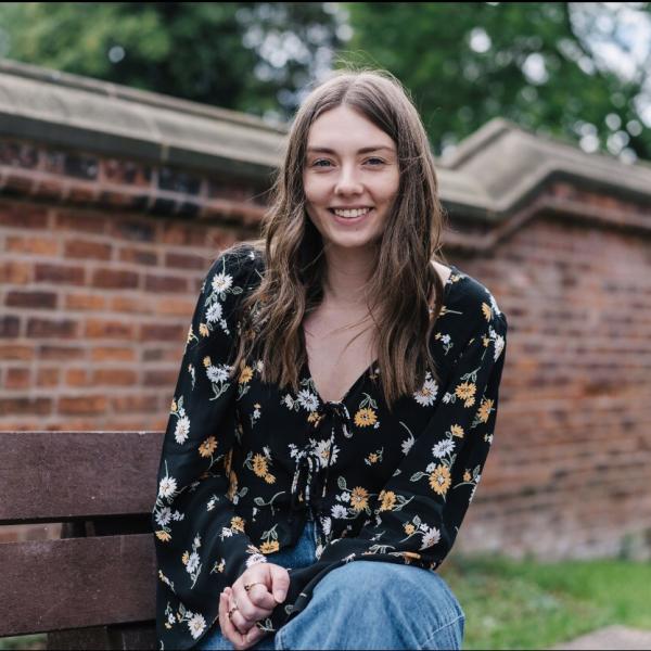 Profile picture of Caroline Lilley in the law school garden with boundary wall behind her