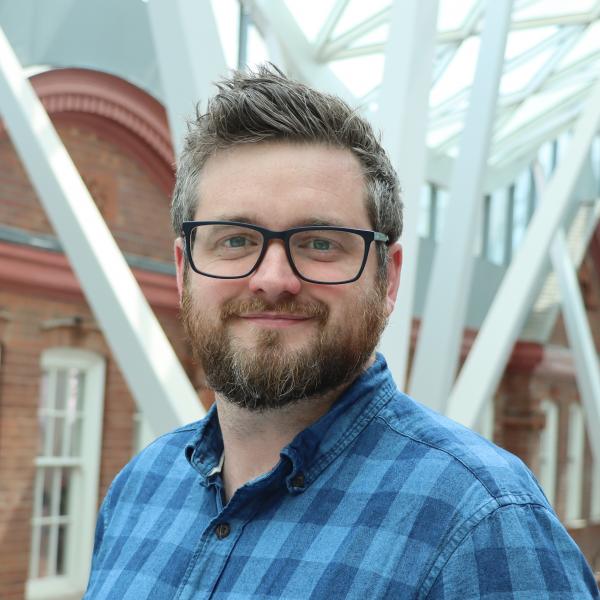 Profile picture of A white man in a blue checked shirt wearing glasses