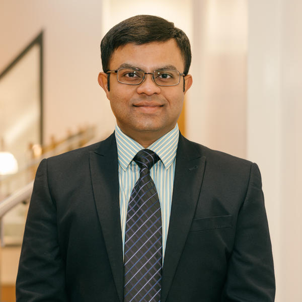 Profile picture of Avik Mukherjee wearing a black suit and striped green shirt.