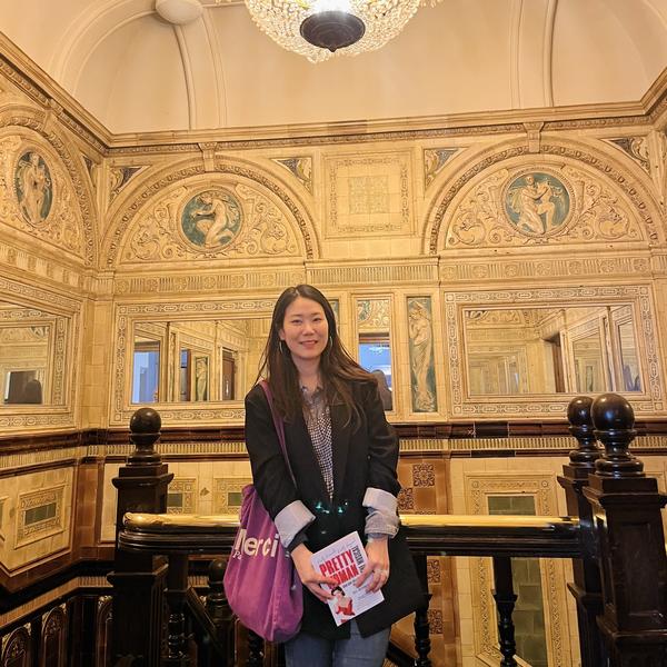 Profile picture of Photo of academic Seungkyung Kim stood in an ornate stairwell with glass chandelier above her