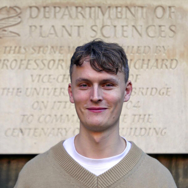 Profile picture of Image of Dr. Christopher Bousfield in front of a beige stone sign reading department of plant sciences