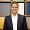 Journalism alumni Dan Walker. He is smiling and standing in front of some colourful blocks. 