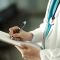 A photo showing a doctor writing on a clipboard