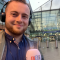 Jacob Waters holding a microphone outside of Manchester Piccadilly train station