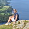 A woman sat on a cliffside in front of a lake