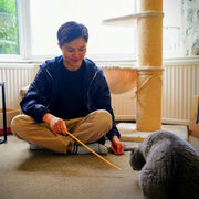 Toshiaki Ito sat on the floor playing with a cat