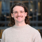 Researcher wearing a jumper and glasses smiling