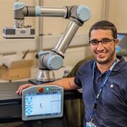 Smiling researcher sitting next to engineering equipment