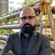 Jacob Nickles stood with crossed arms in front of a selection of small plants