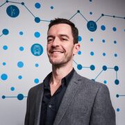 An image of Robert Langley in a suit stood in front of a graphical background.