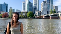 Poltics student Lucy Davis-Jenkins in front of body of water and skyscrapers - Germany