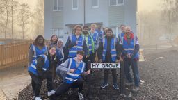 Members of the ChemEngSoc outside the first hydrogen house in the country wearing blue high vis jackets