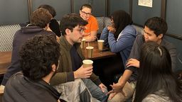 A group of students enjoying drinks and chat around a table in Coffee Revolution