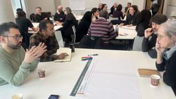A group discussion around a table with flipchart paper and pens on it