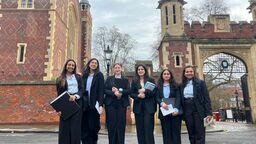 Group of students are smartly dressed outside a fancy red brick building