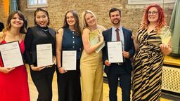 Six people stood full length holding awards.