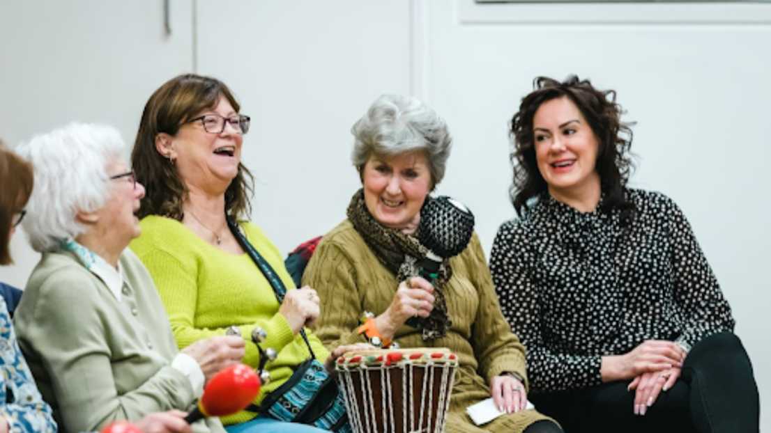 4 women are laughing as they play musical instruments