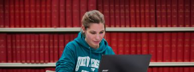 Girl sat with laptop in library