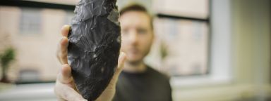 Archaeology student holding up archaeological find 