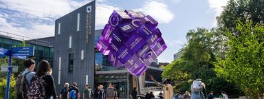 Students walking past Sheffield Students' Union and looking at a purple cube