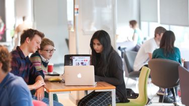 Student sitting around a laptop