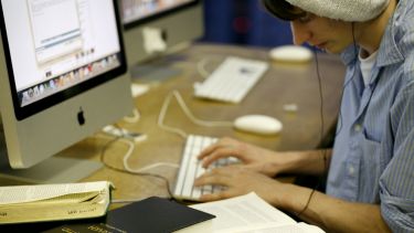 Student on computer with books