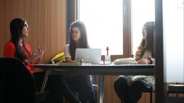 English language and linguistics students sitting around table with laptop