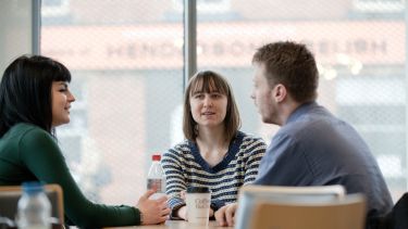 Image of three postgraduate history students sitting around table