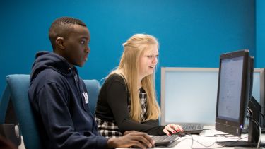 Image of two postgraduate law students on computer with blue background
