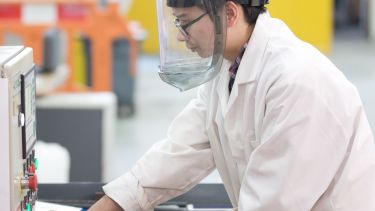 Image of postgraduate materials science and engineering student using equipment with mask