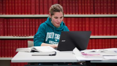 Girl sat with laptop in library