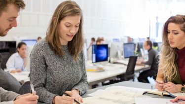 Sheffield graduate working with colleagues at desk at work