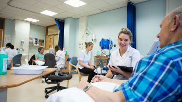 A trainee nurse taking a patient's pulse.