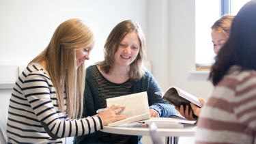 Postgraduate students reading together in the common room